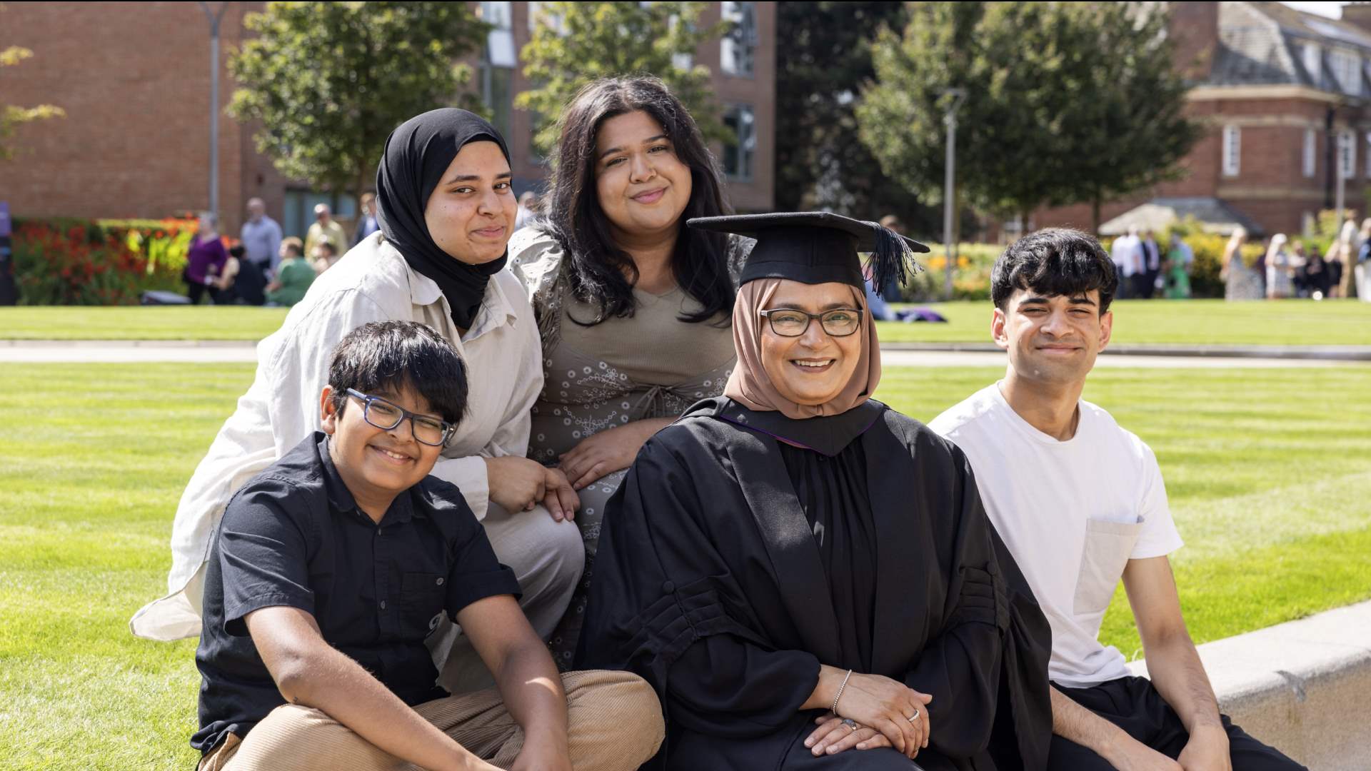 Rehmatun Mohtat in her cap and gown sat outdoors with her four children