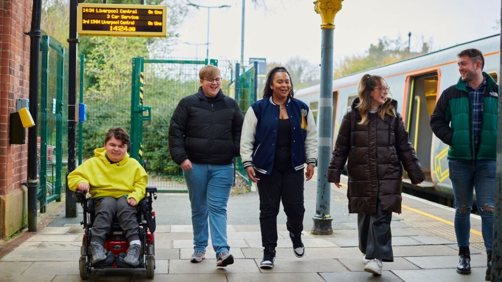 Students meet on the platform and chat whilst waiting for the train to Liverpool