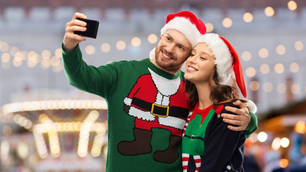 two students smiling while taking a selfie with Christmas jumpers on