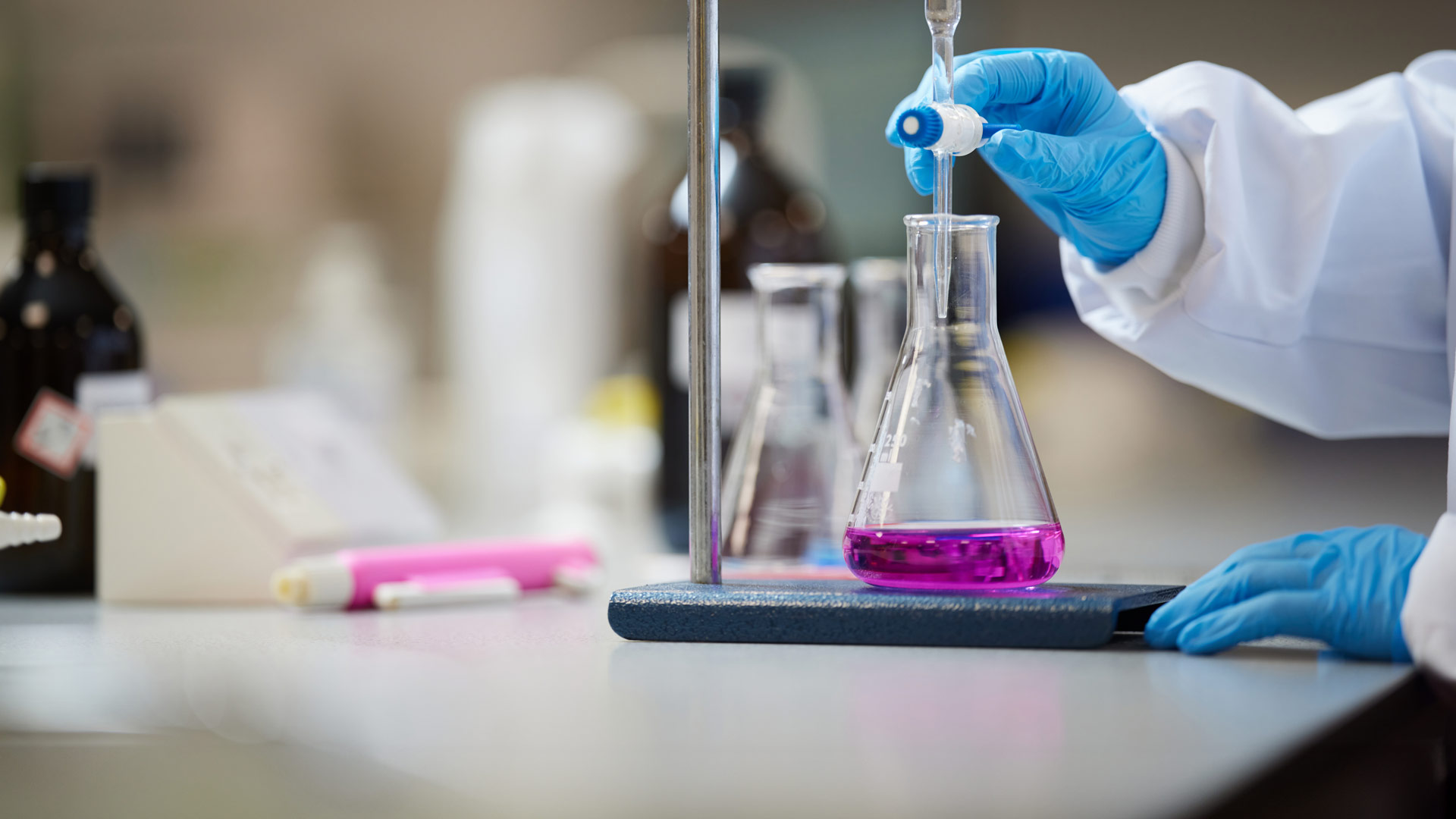 An image of someone using chemistry equipment, pouring liquid into a glass flask