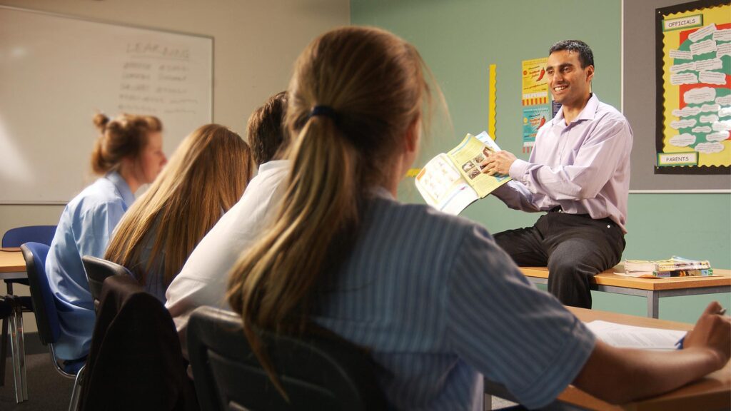 A trainee teacher speaks to a classroom of secondary school students