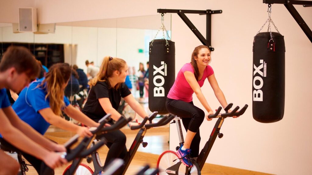 Four students participate in a spinning class.