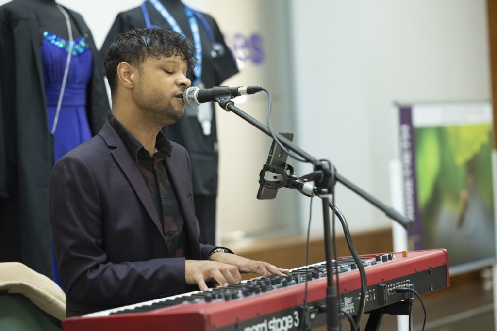 Alumnus Taylor Paisley-French playing the keyboard and singing