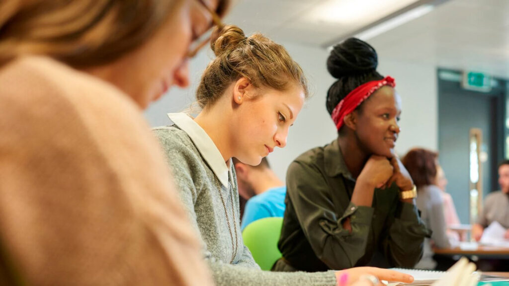 A student makes notes as she participates in a seminar.