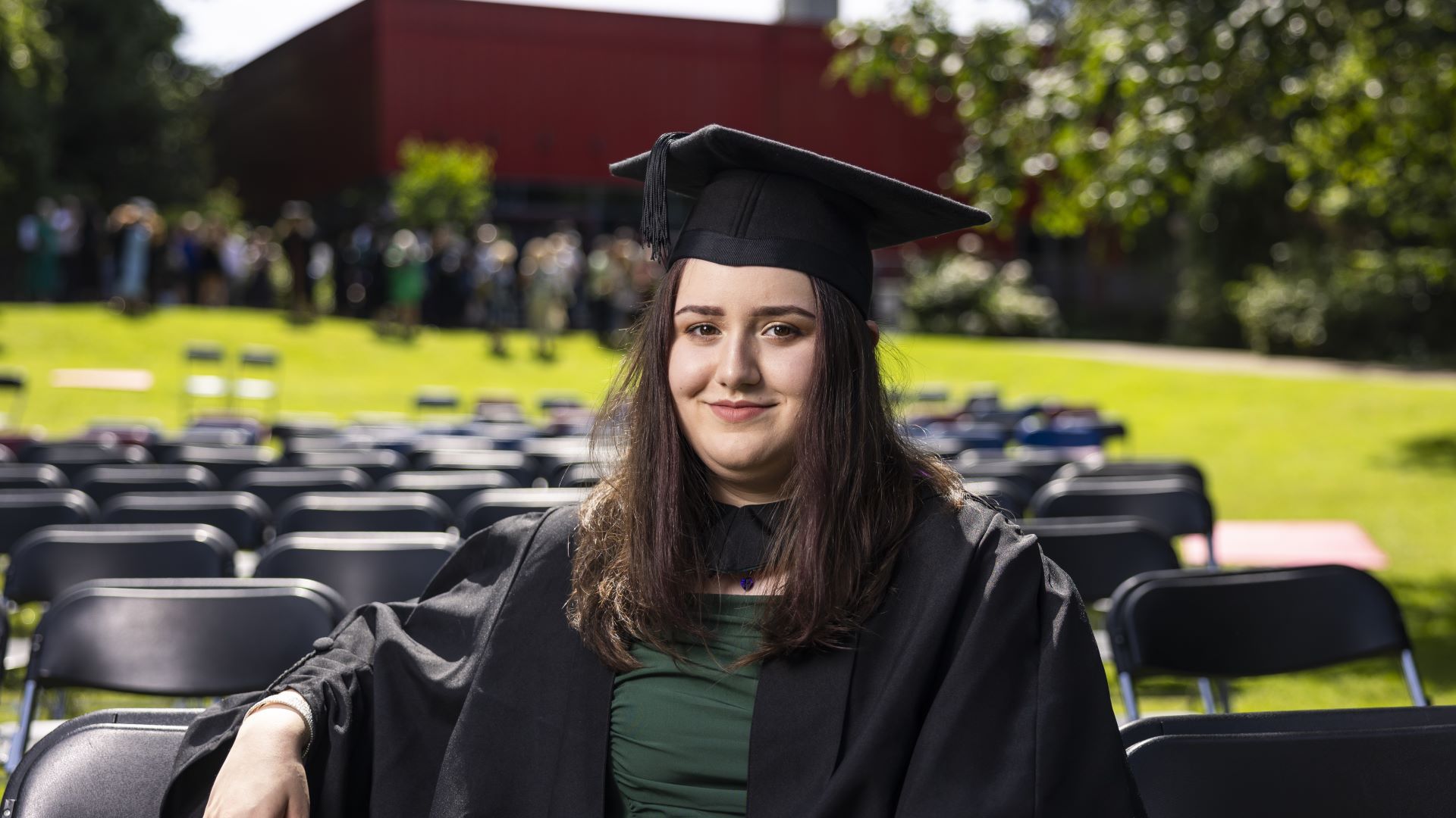 Emily Stirrup sits on the front row of an area of foldable chairs in front of the big screen.