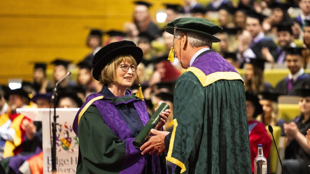 Dame Louise Ellman holds a scroll and shakes hands with VC John Cater