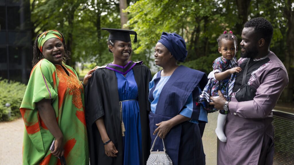 Racheal Babarinde stands surrounded by four family members wearing colourful celebration outfits.