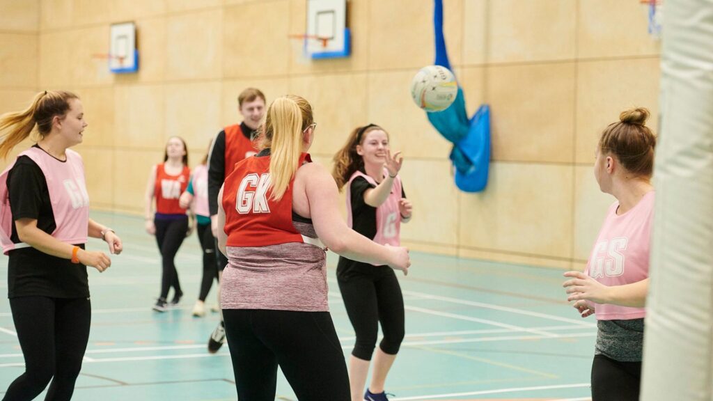 A group of students playing netball in the sports centre.