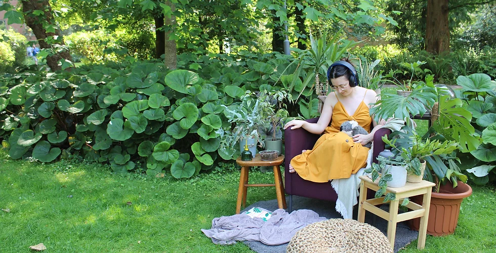 Student in headphones, sitting in a garden surrounded by plantlife.