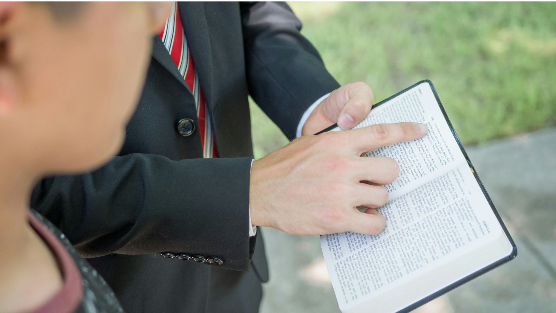 Man in a suit pointing to a page in the Bible.