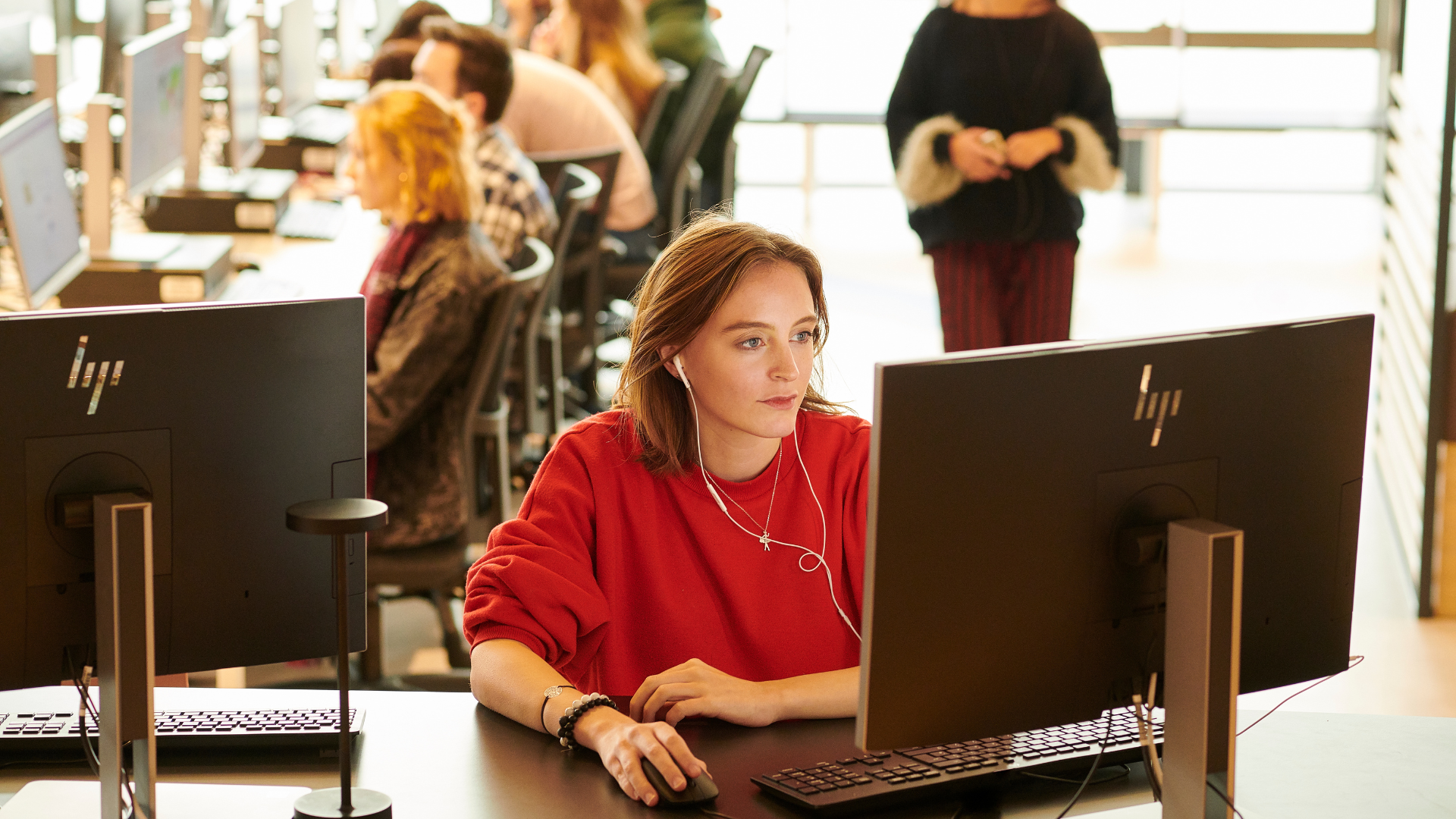 Student using a PC with headphones in holding mouse